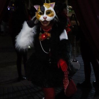 Una integrante de la banda con un tocado de plumas y una máscara de gato.