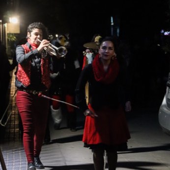 Dos músicos de la banda tocando junto al bombo, de noche.