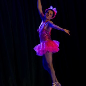 La bailarina en el aire, iluminada de azul y violeta.
