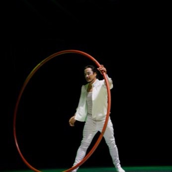Una artista de blanco gira dentro de una rueda Cyr.