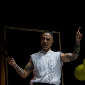El malabarista de chaleco blanco con una pelota amarilla en la mano.