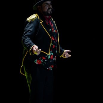 Un artista de traje oscuro y sombrero, solo en la pista.