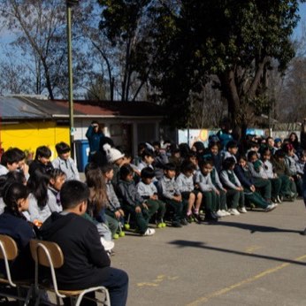 Los niños de la escuela sentados en el patio, esperando que empiece la función.