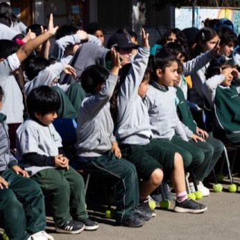 Un grupo de escolares con las manos en alto, riéndose.