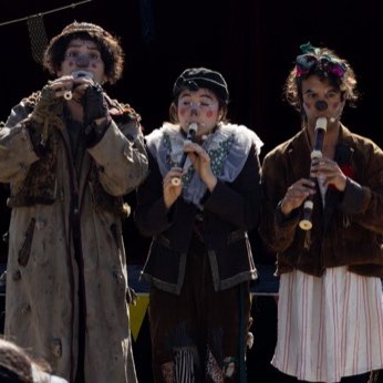 Los tres artistas cantando juntos frente al micrófono.