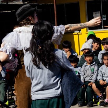 Una artista se acerca a los niños sentados en primera fila.