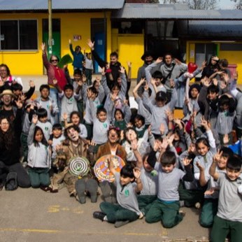 Fotografía de grupo: todo el colegio y la compañía, con los brazos arriba.