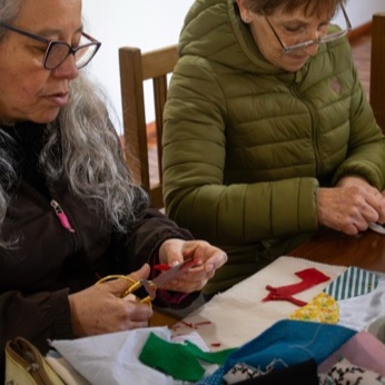 Una participante recorta una figura de tela con tijeras sobre su arpillera.