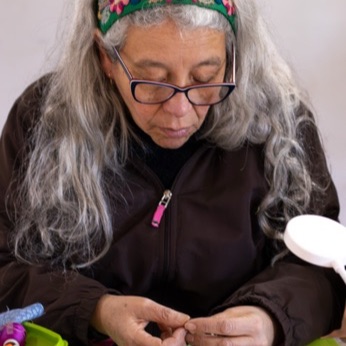 Retrato de una participante enhebrando la aguja sobre su bordado.
