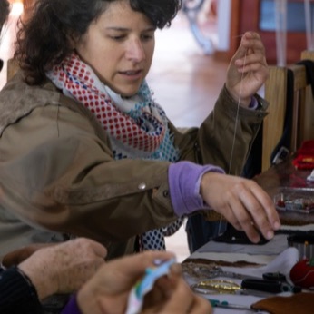 Una mujer estira el hilo después de enhebrar la aguja.