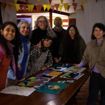 El grupo posa detrás de la mesa, con todas las arpilleras terminadas extendidas encima.