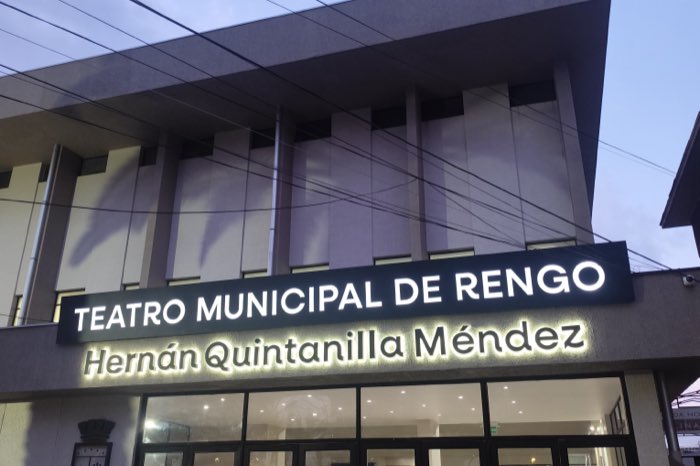 Fachada del Teatro Municipal de Rengo al atardecer, con el letrero iluminado sobre la entrada de cristal.