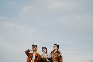 Los tres de pie mirando hacia arriba, muy pequeños contra un cielo nublado que ocupa casi toda la imagen.