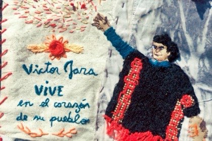 Arpillera bordada con la figura de Víctor Jara con el brazo en alto y la frase «Víctor Jara vive en el corazón de su pueblo».
