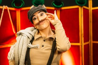 Retrato de una artista caracterizada con gorra y bigote postizo.